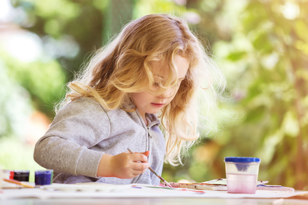 portrait of little blonde girl painting, summer outdoor