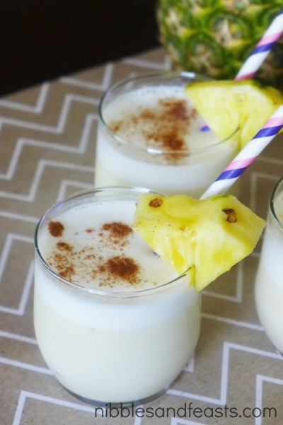 A child happily holding a glass of Kid-Friendly Piña Colada with a straw and pineapple garnish