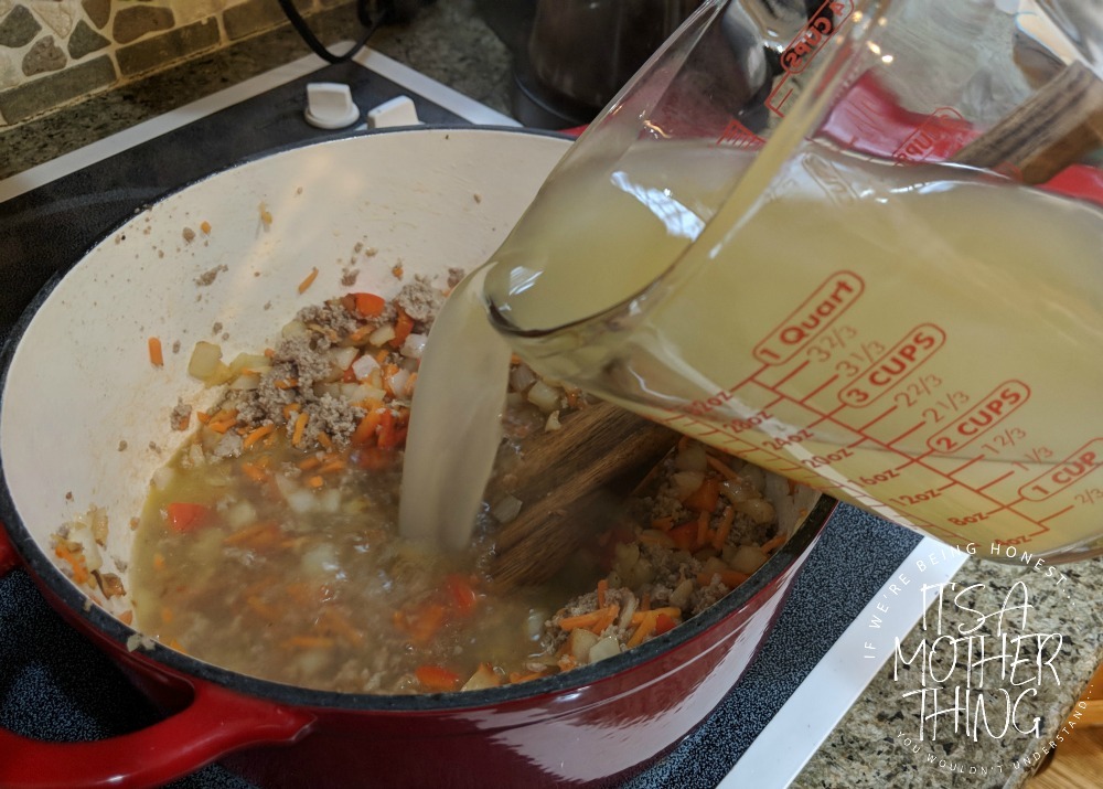 adding chicken broth into a pot