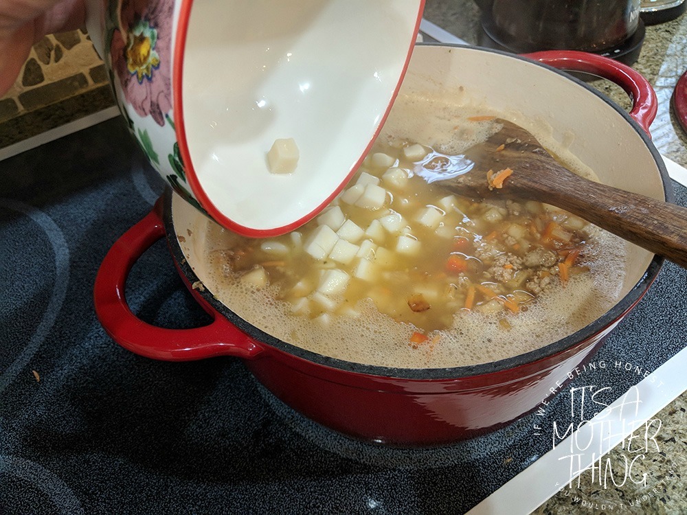 adding potatoes into a soup